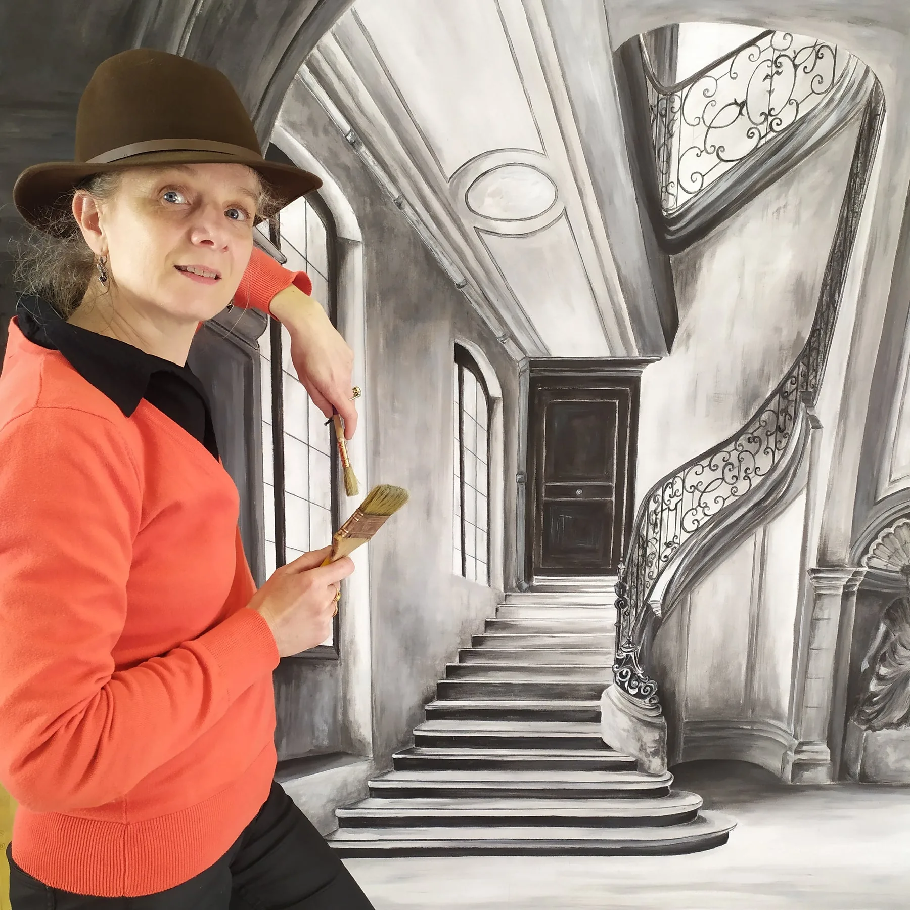 Fabienne Goubaud devant un décor d'escalier en trompe-l'œil